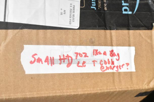 Cardboard box with handwritten label reading "Small HD 702 in a bag, LCD & T cable, charger?"