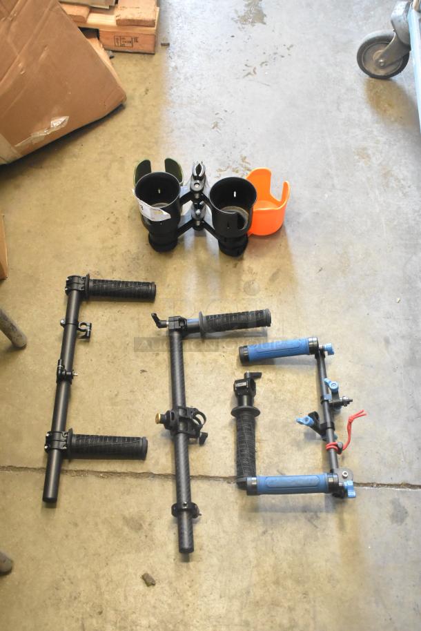Lot of various frame pieces on concrete floor, includes black handles and clamps in good condition. No visible labels.