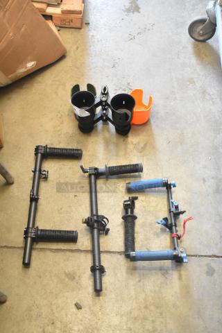 Lot of various frame pieces on concrete floor, includes black handles and clamps in good condition. No visible labels.