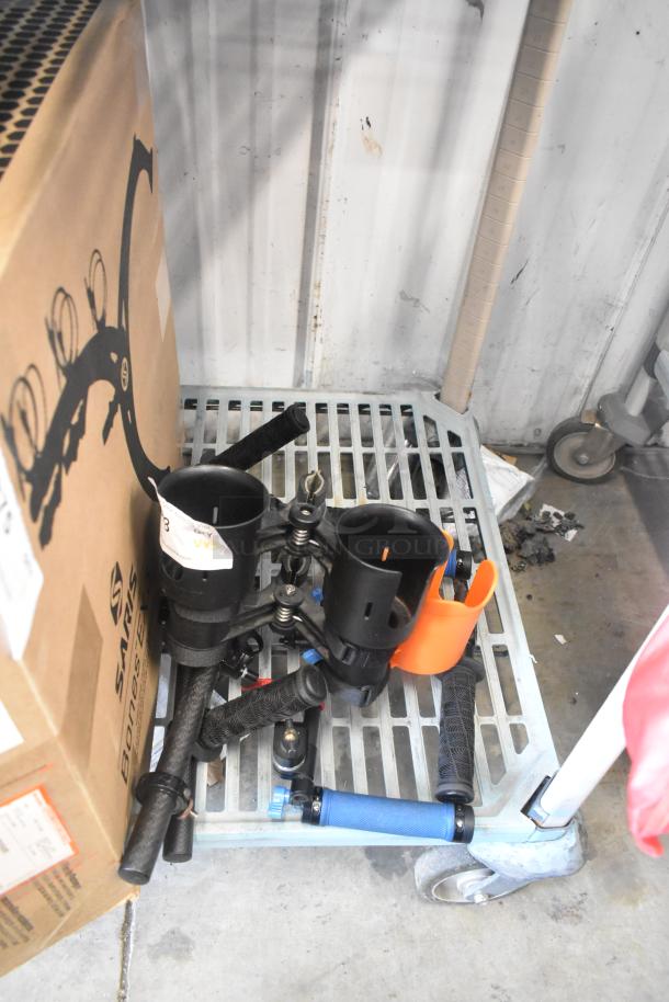 Lot of various items including frame pieces, black holders, grips, and an orange accessory, on a metal cart. Signs of wear.