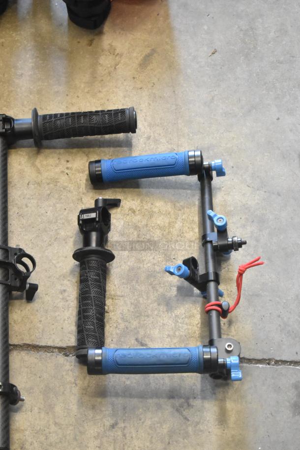 Lot of various camera rig frame pieces, including grips and rods, featuring brands like Redrock Micro and 1A Tools.