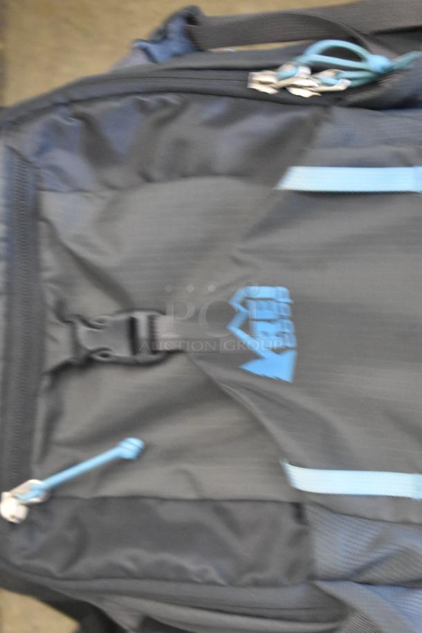 Two black soft bags with light blue accents, featuring a visible logo and sturdy zippers. Good condition.