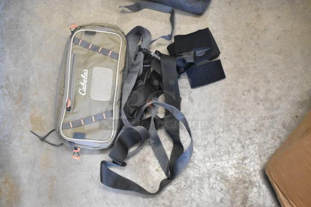 Gray Cabela's soft bag with straps and fastenings, in good condition, lying on a concrete floor.
