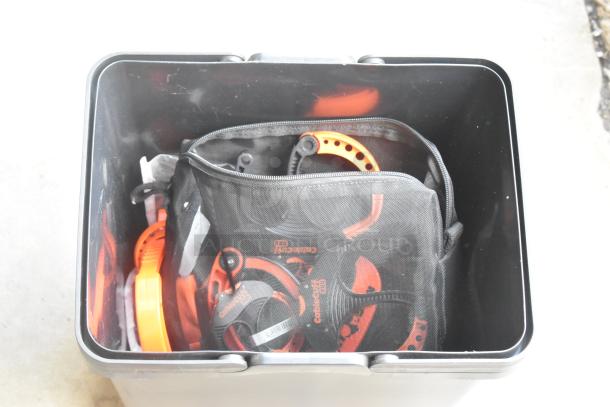 Lot of clamps in a black poly bucket, includes orange circle and spring clamps. Some are stored in a mesh bag.