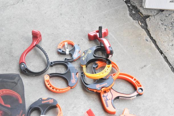 Lot of assorted clamps in various colors and sizes, including CableCuff and Mega Cuff brands, on concrete floor.