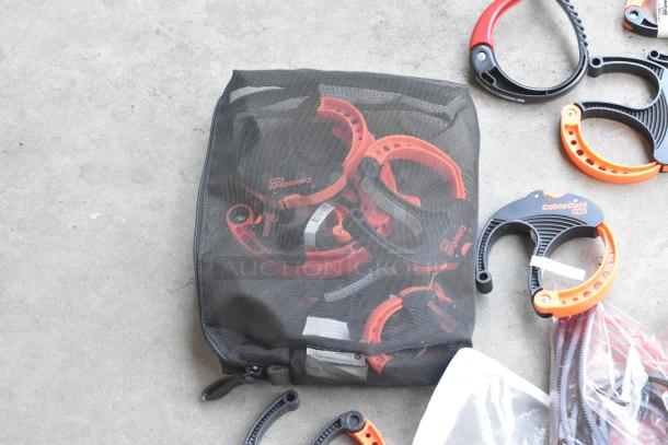 Lot of assorted CableCuff PRO clamps in mesh bag and loose on concrete, various sizes and colors, in good condition.