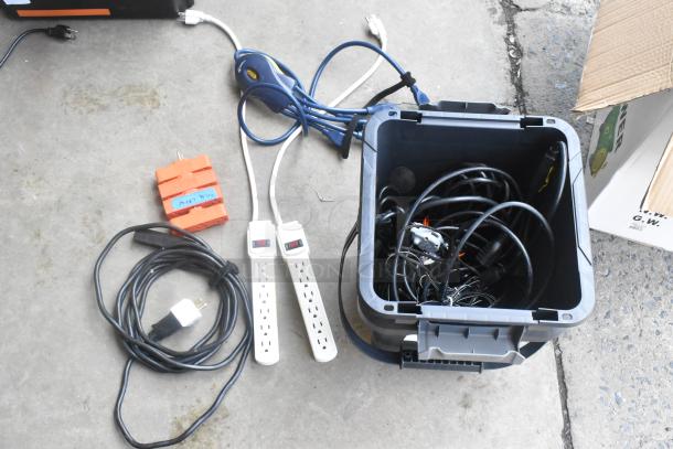 Lot of various cords, adapters, and power strips in a gray poly bin. Includes labeled orange adapter. Mixed condition.