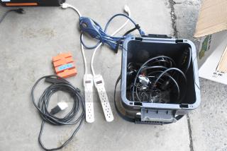 Lot of various cords, adapters, and power strips in a gray poly bin. Includes labeled orange adapter. Mixed condition.