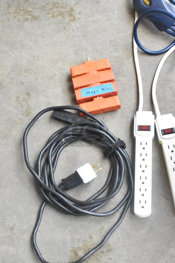 Lot of assorted cords and adapters in a poly bin; includes extension cables and orange three-way splitter marked "FILM CREW."