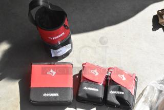 Four Husky tool bags in red and black, including one bucket, one pouch, and two smaller cases. New condition with labels.