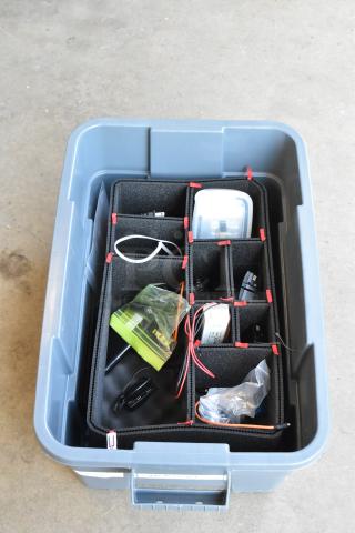 Lot of various items in a poly bin, includes DigiPro units and Harbortronics battery charger. Dividers organize contents.