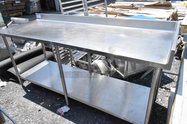 Stainless steel table with under shelf and backsplash, featuring a polished surface. Slight signs of wear; ideal for commercial use.