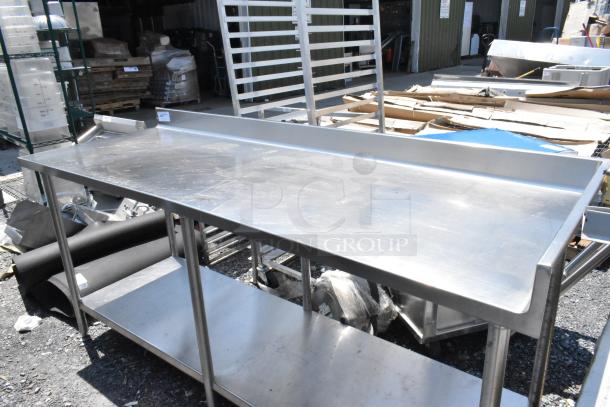 Stainless steel table with under shelf and back splash, in good condition. Ideal for kitchen or industrial use.