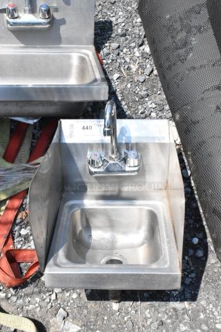 Stainless steel single bay wall mount sink with faucet and handles, slightly worn, includes label with auction details.