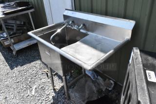 Stainless steel single bay sink with right-side drain board, faucet, and handles. Suitable for commercial use.