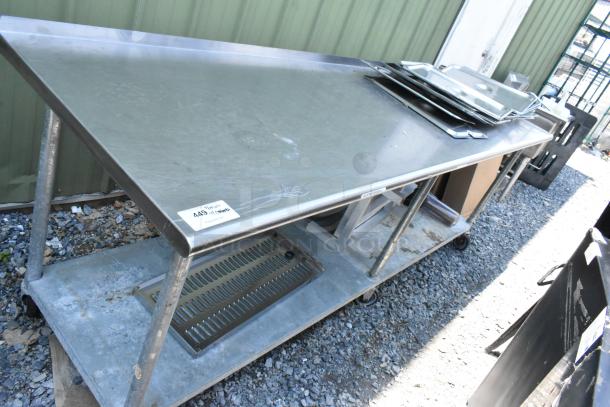 Stainless steel table with under shelf, includes dunnage racks and metal pans. Good condition with visible use. Auction tag 449.