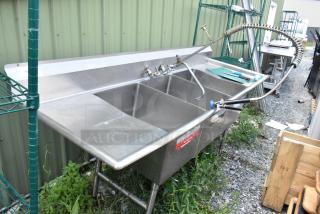Stainless steel 3-bay sink with dual drain boards, handles, and spray nozzle. Suitable for commercial kitchens. Good condition.
