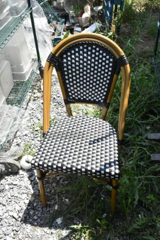 Brand new wicker-style patio chair with a black and white checkered pattern. Minor scratches and dents.