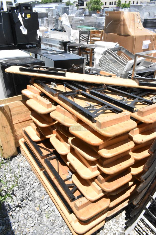 Stack of 47 folding tables with wooden tops and black metal frames. Good condition. Ideal for events or bulk purchase.