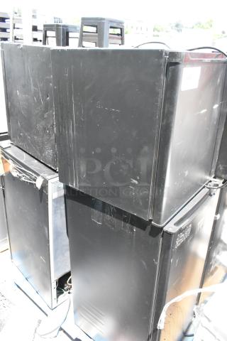 Eight black mini coolers, used, various brands including Haier, Galanz, Hamilton Beach, Hisense, Frigidaire, visible scratches.
