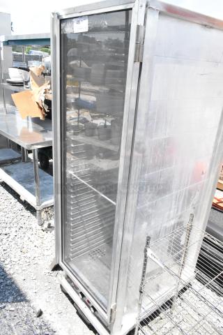 Omcan metal commercial heated holding cabinet on casters, 115V, 1 phase. Visible shelves, sturdy construction, used condition.