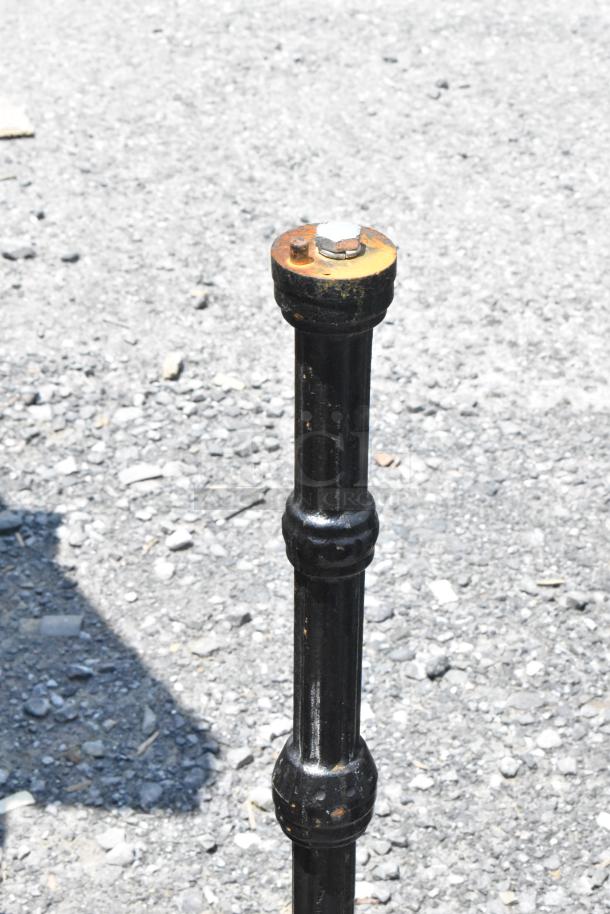 Black metal table base with rust at top, suitable for supporting a tabletop. Auction item includes seven bases with one tabletop.