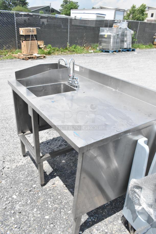 Stainless steel table with two single sink bays, faucets, and handles. Durable design, ideal for commercial use. Good condition.