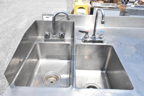 Stainless steel table with two single sink bays, chrome faucets, and handles. Slight wear, industrial use.