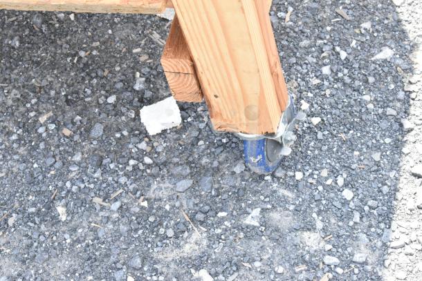 Wooden table leg with blue commercial caster, showcasing sturdy construction and mobility features.