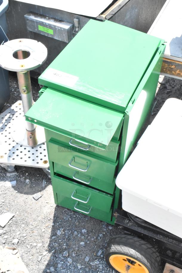 Green metal filing cabinet with three drawers, minor surface scratches. Auction label "493" on top. Sturdy condition.