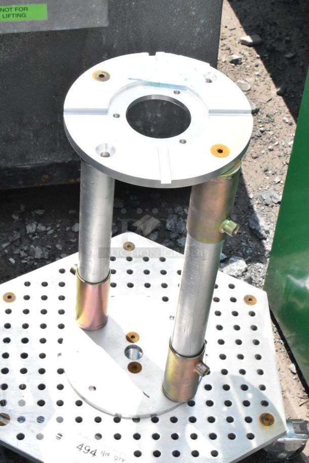 Metal unit on commercial casters with perforated base, cylindrical supports, and top plate. Sturdy construction, like-new condition.