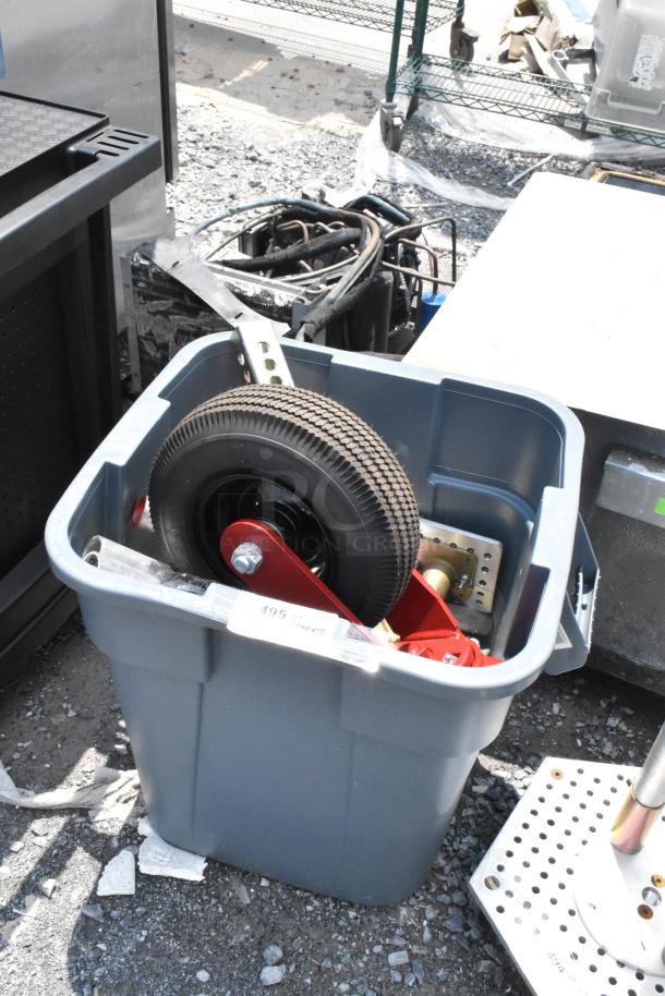 Blue poly trash can filled with assorted metal parts and a large rubber wheel, showing signs of use. Marked with label "495".
