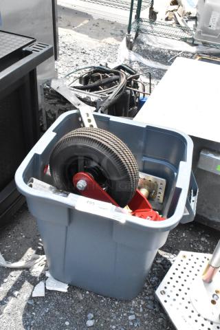 Blue poly trash can filled with assorted metal parts and a large rubber wheel, showing signs of use. Marked with label "495".