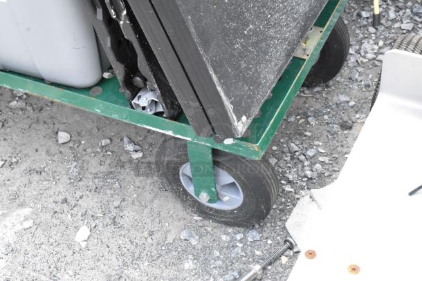 Green metal flat cart with contents, includes a folding table and poly bin. Appears used, with visible wear on wheels.