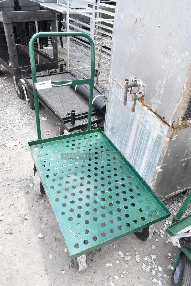 Green metal flat cart with perforated surface, four wheels, and push handle; item tag "499" visible; used condition.