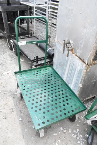 Green metal flat cart with perforated surface, four wheels, and push handle; item tag "499" visible; used condition.