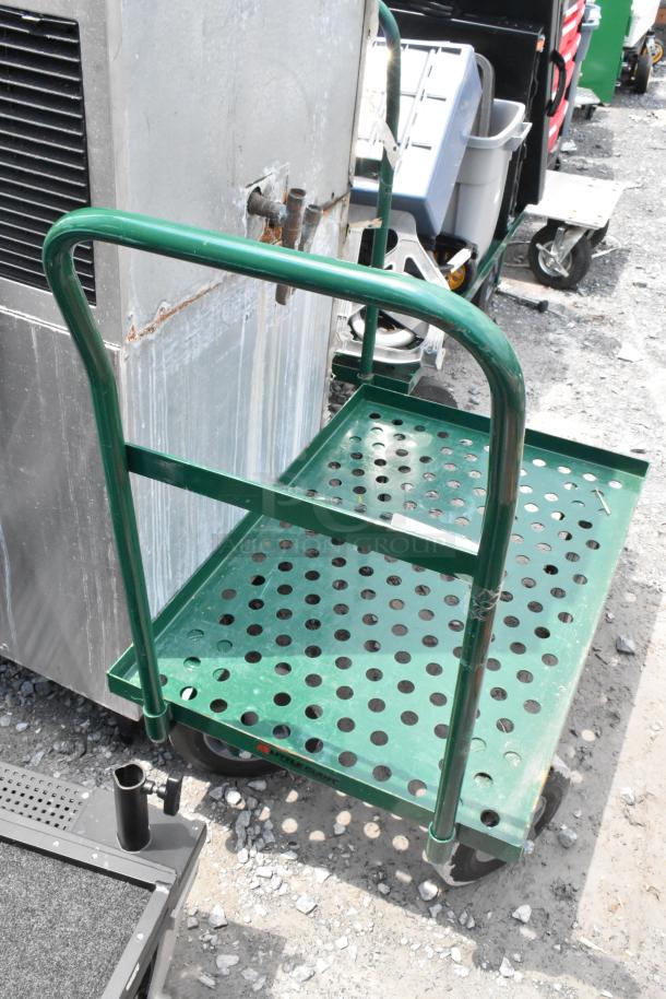 Green metal flat cart with perforated platform, sturdy handle, and casters. Suitable for heavy-duty use. Slightly worn.
