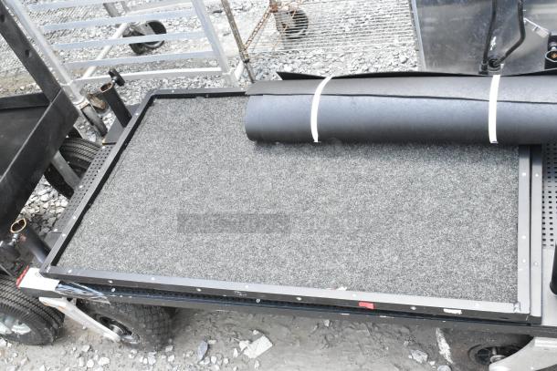 Cart on casters with a carpeted surface and black frame, in good condition. Features heavy-duty wheels for easy movement.