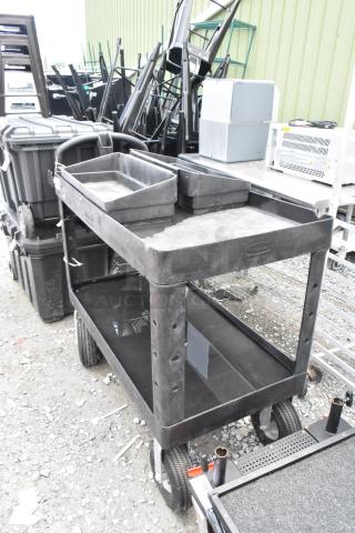 Black poly 2-tier cart on casters, sturdy construction with upper and lower shelves, textured surface, in good condition.