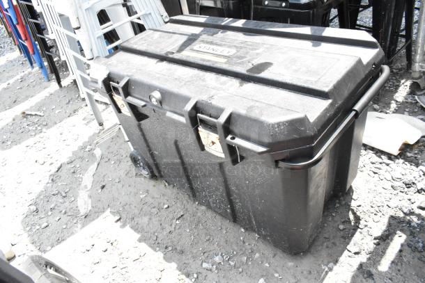 Stanley black poly case on casters, used condition, visible dirt, two latches, side handle, and brand label on lid.