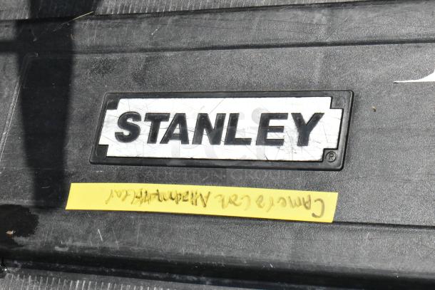 Stanley black poly case with casters, showing brand label. Worn surface indicates previous use.