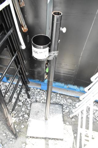 Metal stand with square base and vertical pole, black finish, features a cylindrical attachment. Marked with "506" label.