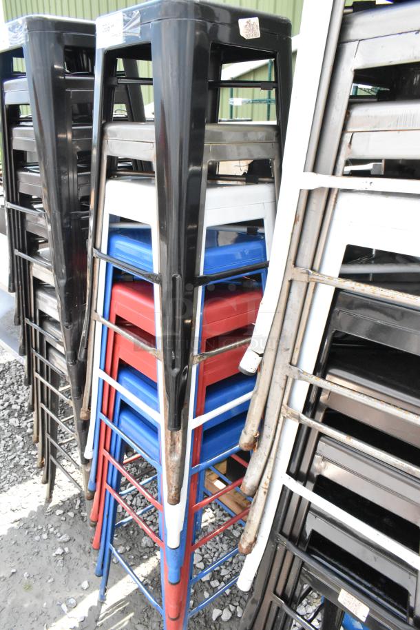 10 colorful metal Tolix-style bar height stools stacked, in good condition. Durable design, ideal for commercial use.