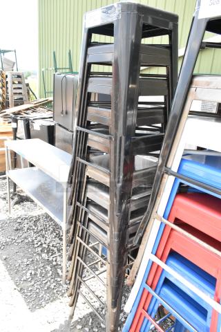 Stack of 9 black metal Tolix-style bar height stools, robust and stylish, suitable for both indoor and outdoor use.