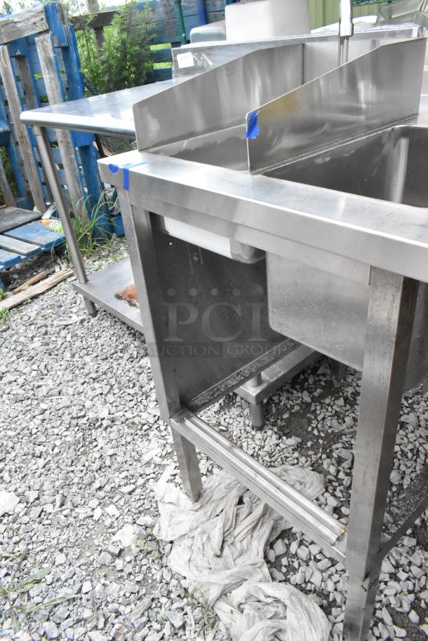 Stainless steel table with two single sink bays and faucets. Pre-owned, visible wear on edges, suitable for commercial use.