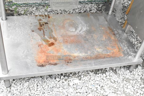 Stainless steel table with rust and wear, featuring an under shelf and back splash. Ideal for industrial use.
