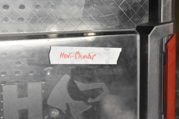 Poly bin containing various items with a label reading "Movi Elevator." Clear plastic surface with partial visible content.