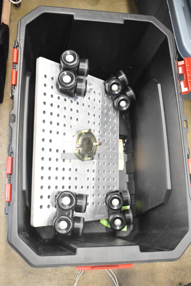 Poly bin containing various items including a Movi Elevator with rollers and perforated metal base. Ideal for equipment transport.