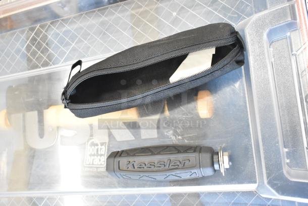 Poly bin with various items including a Kessler handle and a black zippered pouch on a Husky surface.