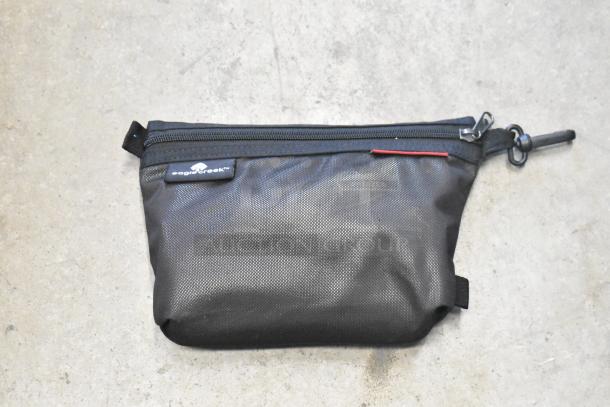 Black Eagle Creek pouch with zipper, textured fabric. Brand logo tag visible. Appears in good condition.